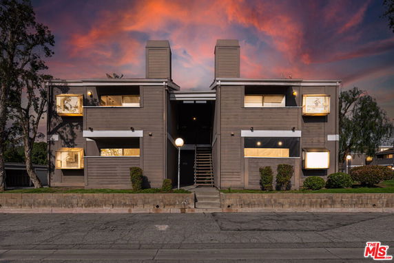Front view of a two-story building with a central staircase and chimneys at dusk.