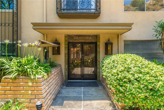 Front view of a building entrance with decorative iron door and brick planters.