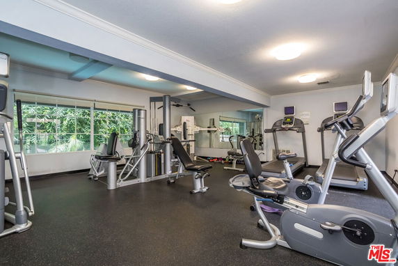 Indoor gym area with various exercise equipment, including treadmills and weight machines.
