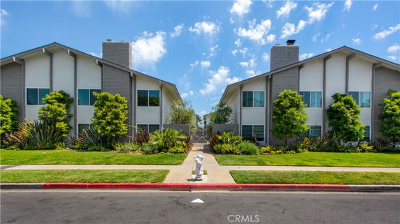 Front view of two adjacent two-story houses with chimneys and large windows.
