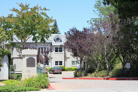 Front view of a two-story building with a shingled roof and surrounding landscaping.