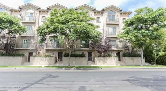 Front view of a multi-story residential building with balconies and trees.