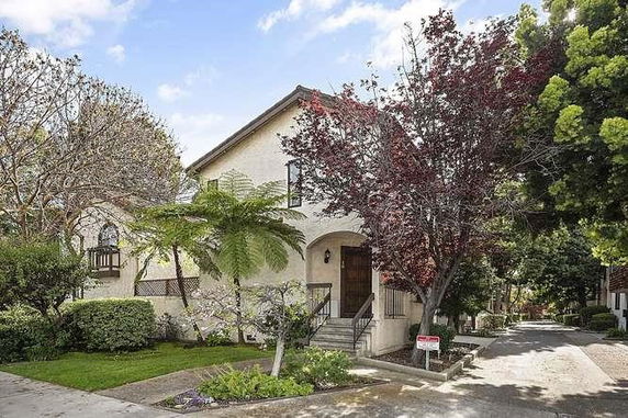 Front view of a two-story house with an arched entrance and surrounding trees.