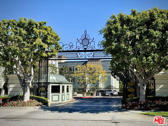 Front view of a gated residential complex with decorative ironwork and security booth.