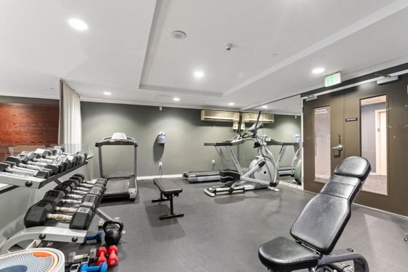 Room equipped with gym equipment including treadmills, exercise bikes, and weights.