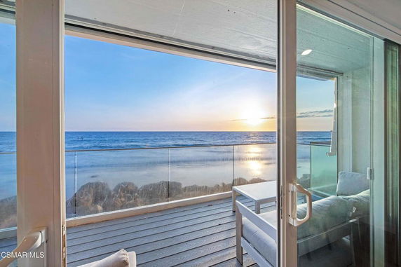 View of the ocean from a building's balcony during sunset.