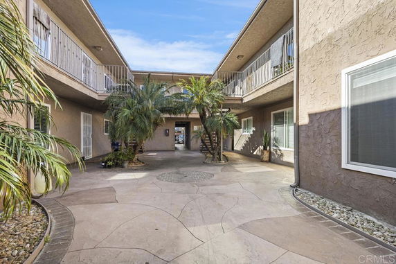 Courtyard of a two-story building with palm trees and balconies.