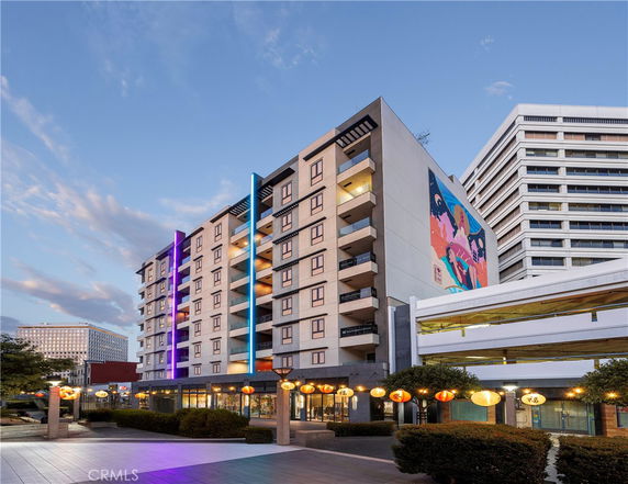 Front view of a multi-story building with colorful vertical lights and wall art.
