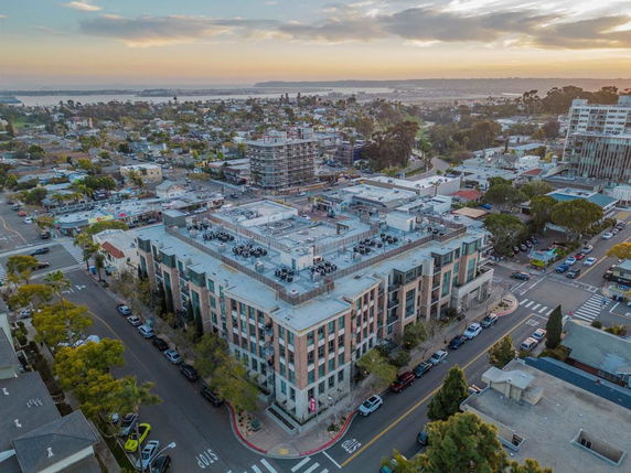 Aerial view of a large multi-story building with rooftop features in an urban area.