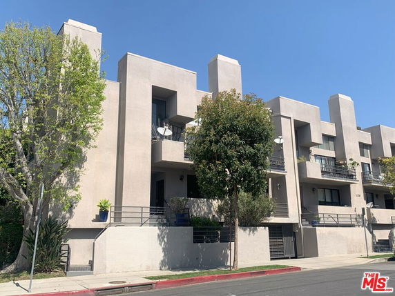 Front view of a multi-story apartment building with balconies and modern architecture.