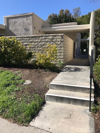 Front view of a modern single-story building with a concrete pathway and steps leading to the entrance.
