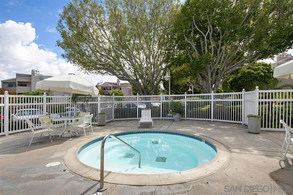 Outdoor view of a small round swimming pool with surrounding fence and patio furniture.