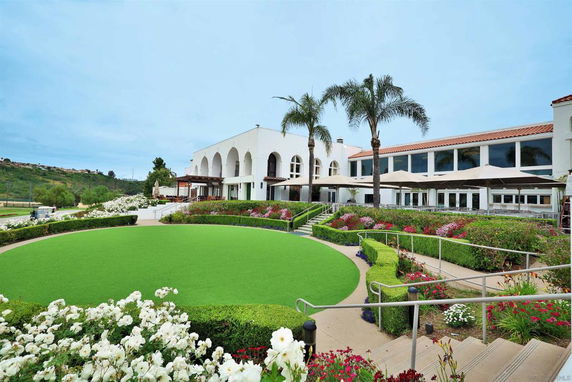Front view of a large building with arched windows and palm trees.