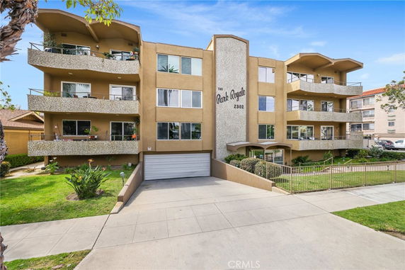 Front view of a multi-story apartment building with balconies and a garage entrance.