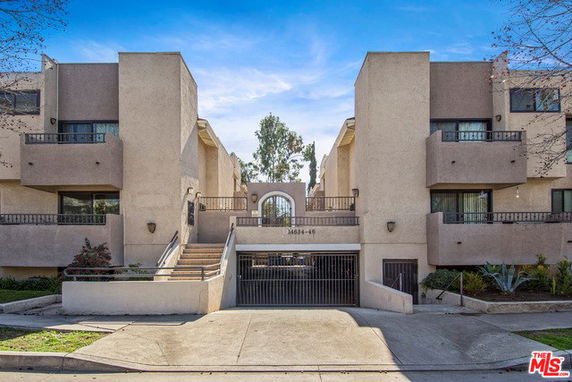 Front view of a multi-story residential building with a gated entrance.