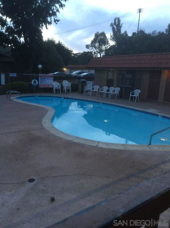 Outdoor swimming pool with chairs around it.