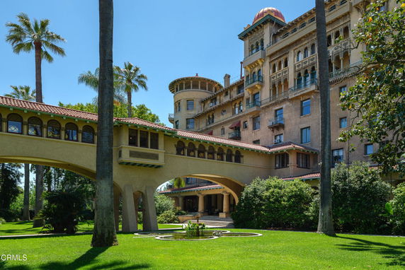 Front view of a large multi-story building with a connecting archway and intricate architectural details.