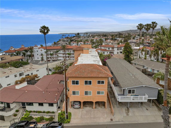 Aerial view of a coastal neighborhood with houses and apartment buildings near the ocean.