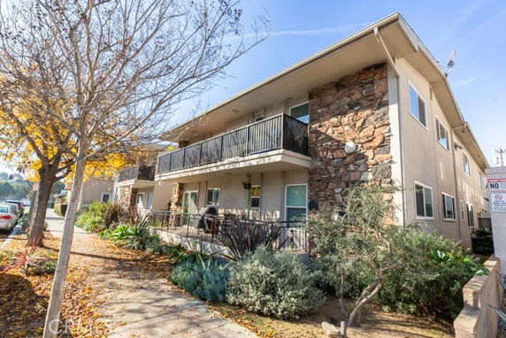 Front view of a two-story apartment building with a balcony and stone facade accents.