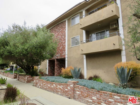 Front view of a multi-story building with balconies and brick accents.