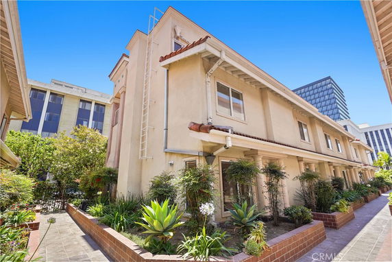 Front view of a multi-story building with a narrow pathway and surrounding greenery.