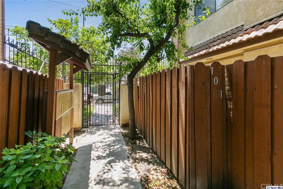 Side view of a house with a wooden fence and a gate.