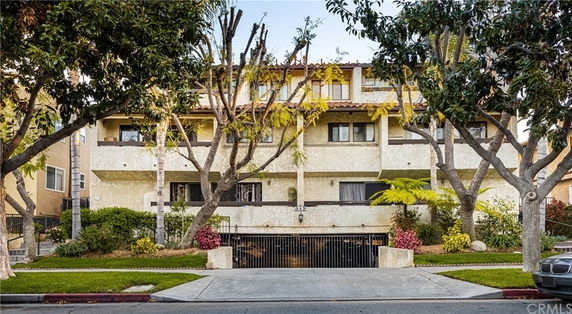 Front view of a multi-story residential building with trees and landscaped areas at the front.