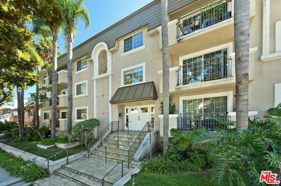 Front view of a multi-story residential building with balconies and a central entrance.