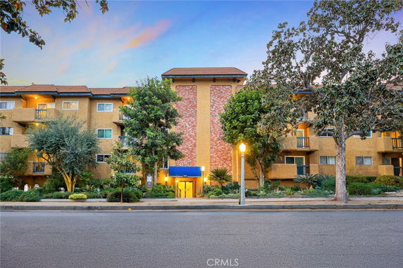 Front view of a multi-story residential building with a central entrance and balconies.