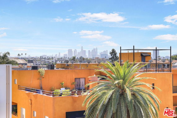 View of orange building with rooftop and city skyline in the distance