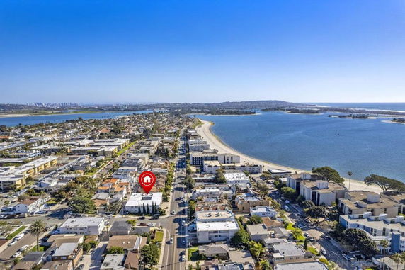 Aerial panoramic view of a coastal neighborhood with buildings and a beachfront.