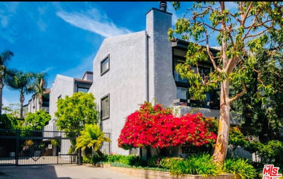 Front view of a multi-story building with a chimney and gated entrance.
