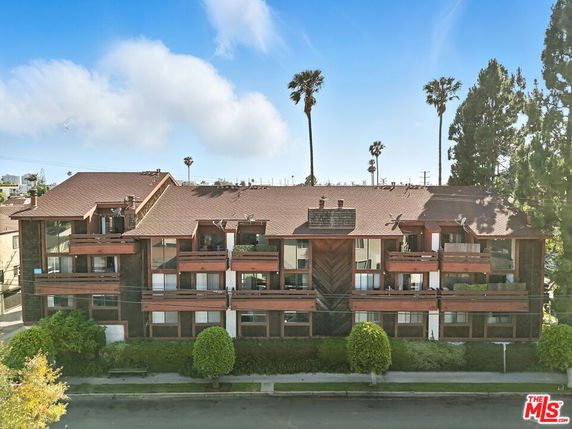 Front view of a multi-story residential building with balconies and a sloped roof.