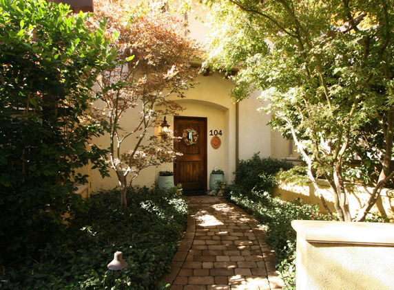 Front view of a house entrance with a wooden door and surrounding greenery.