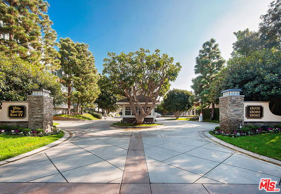 Entrance view of a building complex with trees and signage.