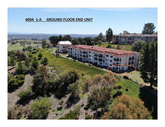 Aerial view of a residential building with nearby greenery and landscape.