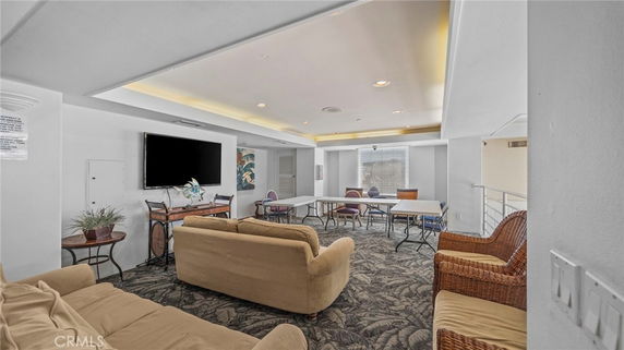 Indoor recreation area with sofas, folding tables, and a TV on the wall.
