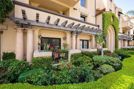Front view of a multi-story building with balcony and greenery.