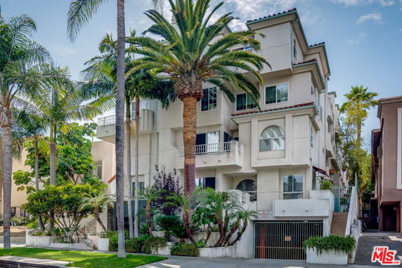 Front view of a multi-story modern apartment building with balconies and an underground garage.