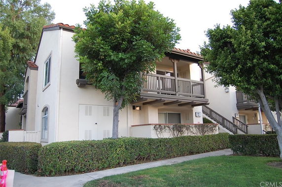 Front view of a two-story apartment building with a balcony and exterior staircase.