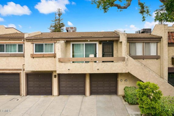 Front view of a two-story townhome with garage doors and a balcony.