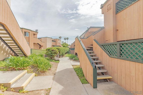 Front view of multi-level wooden residential buildings with exterior staircases.