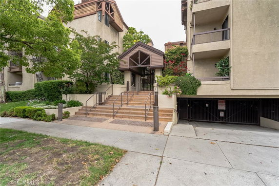 Front view of a multi-story apartment building with an entryway and staircase.