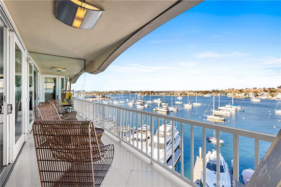 Balcony view overlooking a marina with multiple boats and a clear sky.