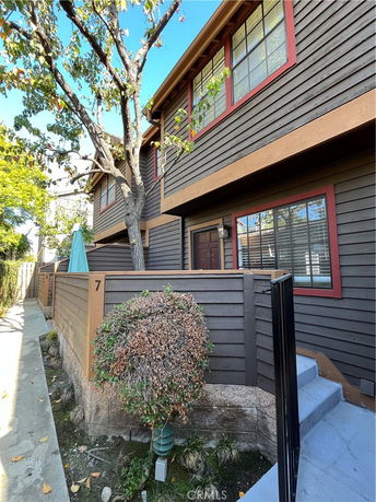 Front view of a two-story building with wood siding and a fenced entrance.