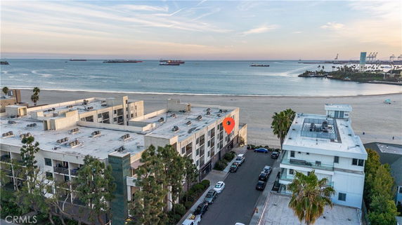 Aerial view of apartment buildings near a beach with ships visible in the ocean.