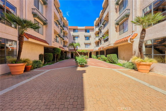 Front view of a multi-story apartment building with balconies and potted plants.