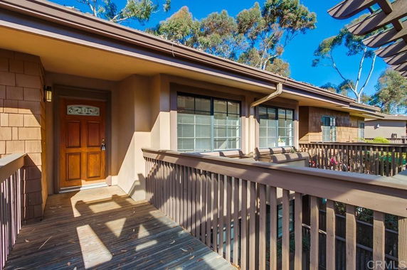 Front view of a house with a wooden entrance and railing leading to the front door.
