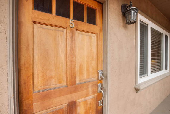 Front view of a house entrance with a wooden door marked with number 5 and adjacent window.