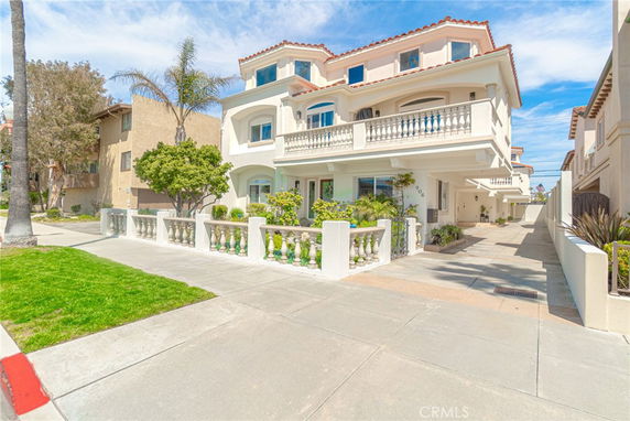 Front view of a multi-story house with balconies and a decorative balustrade.